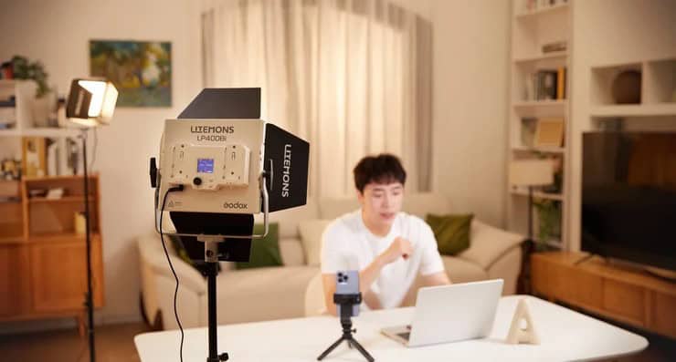Компактная белая панель Godox Litemons LP400Bi со шторками на стойке в комнате стримера перед ноутбуком, на дисплее отображается режим CCT 50% 5600K